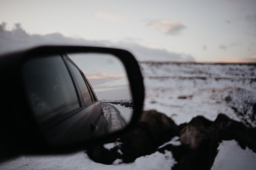A back mirror of a car in Iceland in a snowy landscape