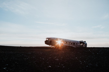 The famous plane wreck in Iceland at a black sand beach with the sun peaking directly through one...