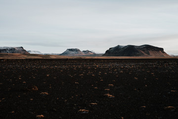 A volcanic field in Iceland at sunset with some mountains in the background.