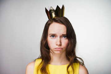 sweet sad girl in a yellow dress is upset, on her head a golden crown did not receive a gift