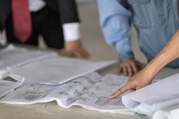 Architect with businessman and engineer are planning on blueprint. Architect is pointing on the blueprint. Selective focus at pointed hand.