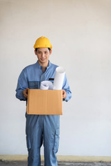 Young Asian technician man with safety helmat carry a brown box of plans.