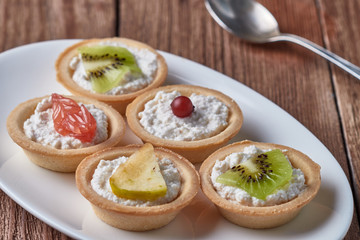 Tartlets with cream, cheese and fruits, cranberries, kiwi, apple, grapefruit.