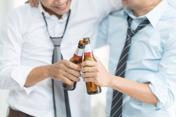 Close-up of The colleague celebrating having a drink after work.Standing together with lifting their bottles of beer. In selective focus on bottles.