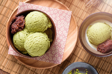 Top view of Homemade green tea or matcha ice cream in the wooden bowl with sweet red bean and put on bamboo mat