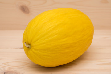 A yellow honey melon with a background of wood.