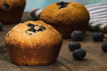 Fresh Blueberry Muffins on a wood table and blue background.