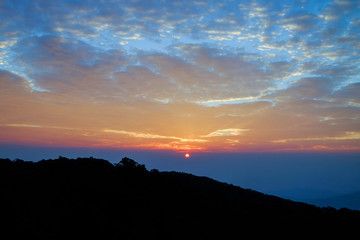 Sun rise blue orange sky background with landscape of mountain and tree with cloudy sky