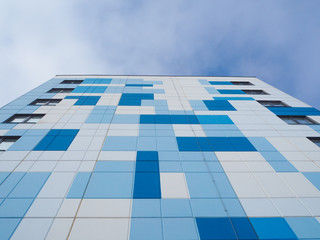 Colored facade wall of a modern residential building with a view from the bottom up against the sky.
