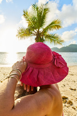 Woman tourist with sarong under coconut palm tree, seychelles