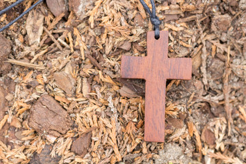 braunes Holzkreuz an einem Band am Boden liegend