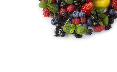 Berries and fruits at border of image with copy space for text. Black-blue and red food. Ripe blackberries, blueberries, strawberries, currants and yellow plums on white. 