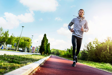 Man jogging in the morning out on the race track - obrazy, fototapety, plakaty