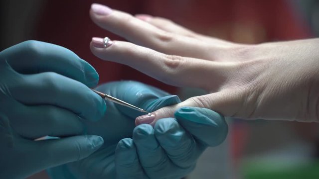 girl decorates nail rhinestones,Nails with manicure covered with nail polish on colored pearls