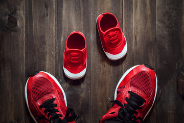 Two red sport running shoes or sneakers of mother or father and child on wooden background,use for...