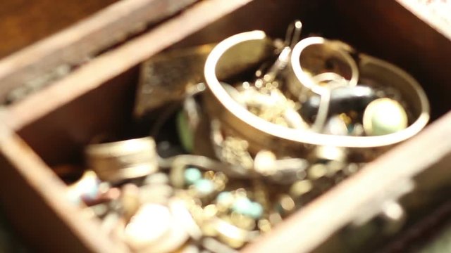 Hand searching in a glowing treasure chest and taking a gold ring. 