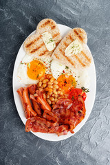 Full english breakfast with egg, sausage and bacon. top view