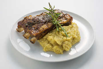 White Round plate with baked pork ribs and cornmeal mush