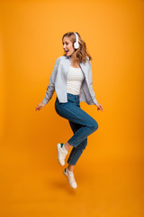 Fototapeta na wymiar Happy young woman jumping listening music