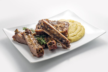 White rectangular plate with baked pork ribs and cornmeal mush