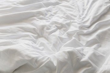 unmade rumpled bed with white messy pillows  in bedroom interior morning light