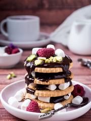 A sweet dessert of chocolate biscuit, raspberry marshmallow and a Cup of coffee on dark background.