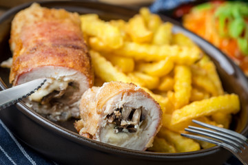 Fried chicken breast stuffed with mushrooms and cheese wrapped in ham served with fries and salad.