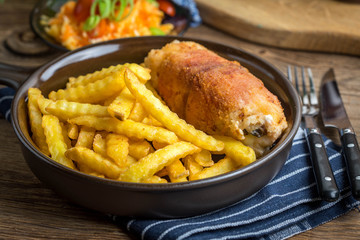 Fried chicken breast stuffed with mushrooms and cheese wrapped in ham served with fries and salad.