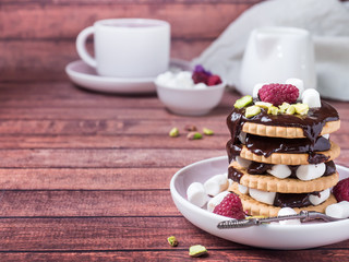 A sweet dessert of chocolate biscuit, raspberry marshmallow and a Cup of coffee on dark background.