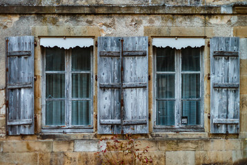Fototapeta na wymiar Old wooden windows with shutters in ancient freench city