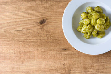 Gnocchi with pesto sauce in plate on wooden table. Top view. Copyspace