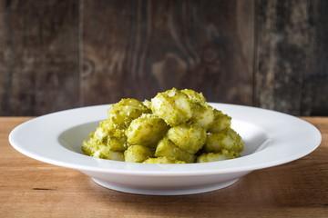 Gnocchi with pesto sauce in plate on wooden table