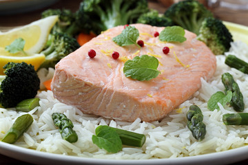 delizioso filetto di salmone cotto al vapore con verdure e riso su sfondo tavolo di cucina rustico