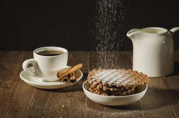 creamer, coffee cup with cinnamon and cookies/white creamer, coffee cup with cinnamon and cookies on a wooden table sprinkled icing sugar. selective focus