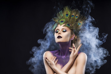 Beautiful big breast girl wearing peacock feathers in her hair and artistic violet shiny body art...
