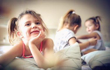 Three little girls playing in bed.