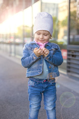 A little girl in jeans wear shows on the street