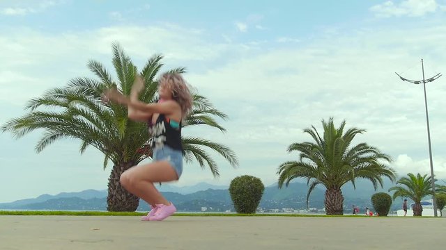 Cool dancing girl against the background of palm trees and mountains