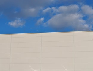Ściana hali fabrycznej na tle błękitnego nieba - obrazy, fototapety, plakaty