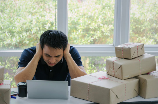 Start Up. Depressed, Disappointed, Stressed. young asian man working with laptop computer and delivery packaging box on table, small business owner working at home office, SME, shopping online concept