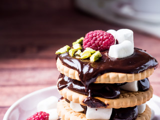 A sweet dessert of chocolate biscuit, raspberry marshmallow and a Cup of coffee on dark background.