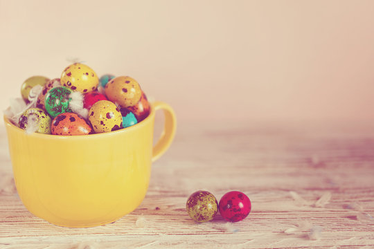 Painted colorful quail eggs in yellow bowl. Easter Spring holiday concept. Toned image
