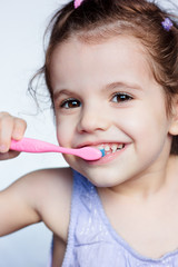 Adorable child girl cleaning teath by toothbrush.