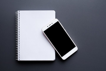 blank white notebook with smartphone over grey desktop - Powered by Adobe