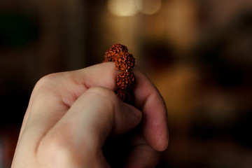 Hand of prayer holding rudraksha beads or rosary.