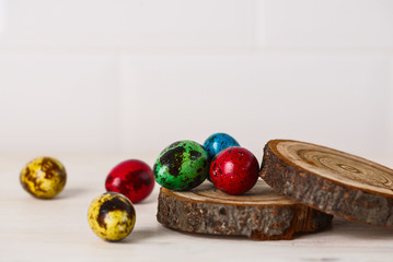 colored quail eggs for Easter on white wooden table