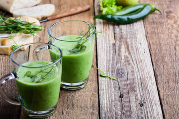 Green pea cream soup in glass mug with sprouts on top