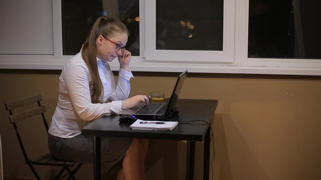 Tired Business Woman With Glasses Working In The Office Laptop Late At Night. Studies Late At Night.Staying Up Late. Overworking.