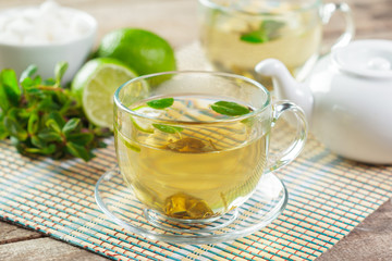 cup of black tea with mint leaves on a wooden table