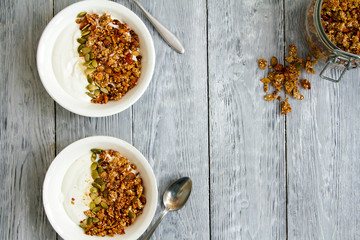 Tasty granola with yogurt in a plate and herbal tea in a glass mug for healthy breakfast. Apartment latitude, top view. Diet, weight loss, healthy eating concept